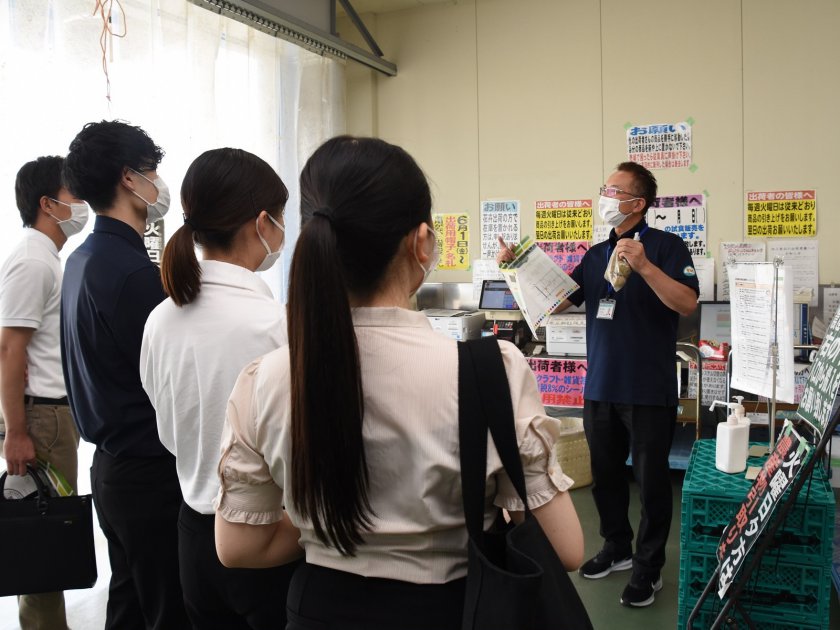 JA農産物直売所「喜ね舎 愛菜館」バックヤードにて説明する同直売所の林智弘所長㊨