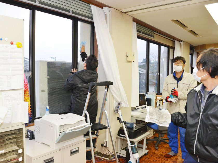 窓ガラスを丁寧に磨き上げる青壮年部員たち