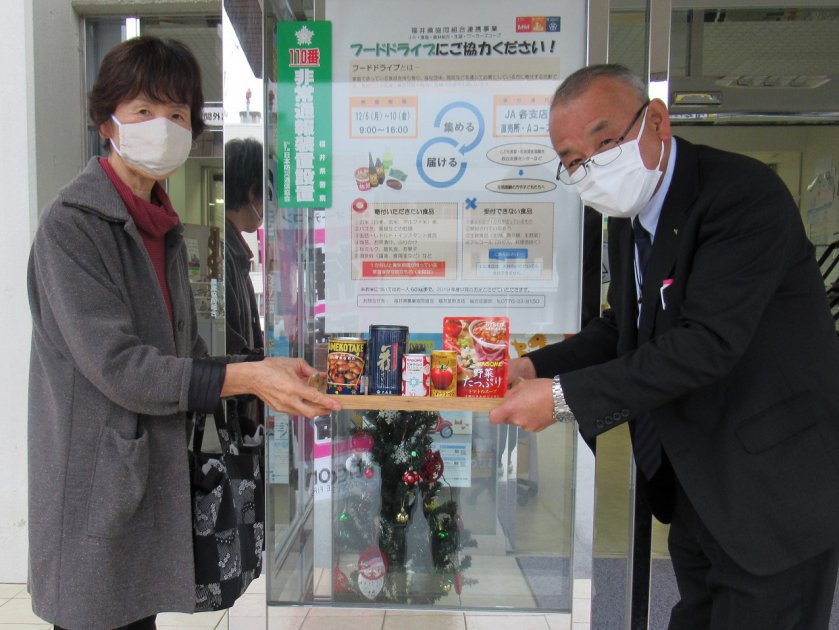 組合員から食品を預かるJA美山支店の竹田支店長㊨