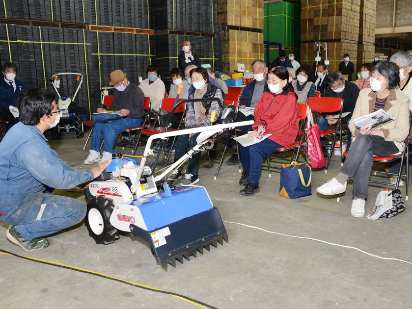 参加者に向けて小型耕うん機のメンテナンス方法を実演してみせるJA福井東部農業施設センターの農機担当者