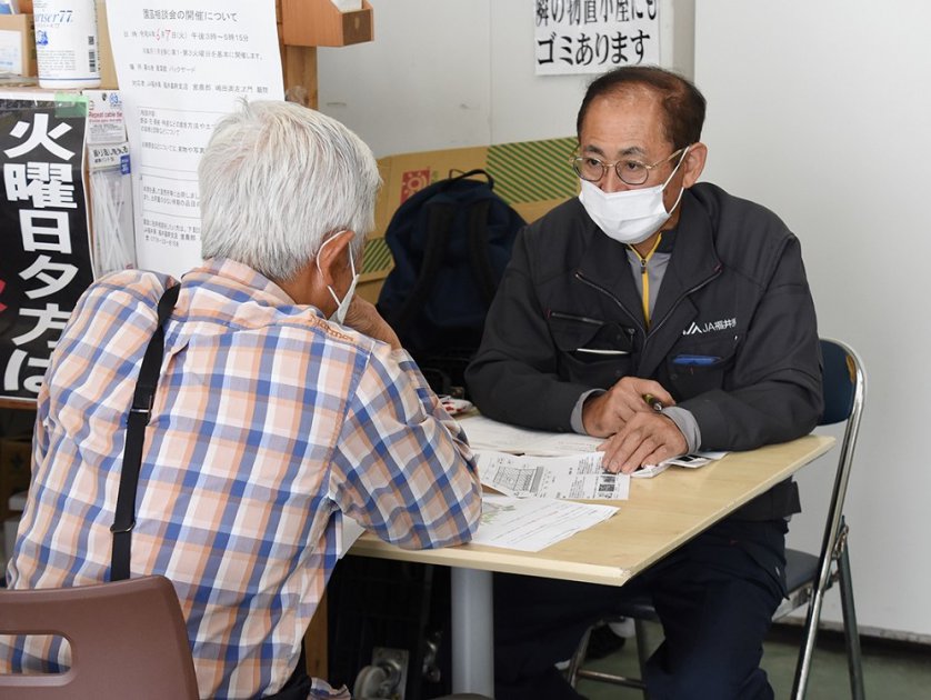 バックヤードで出荷者からの相談を受ける嶋田顧問㊨