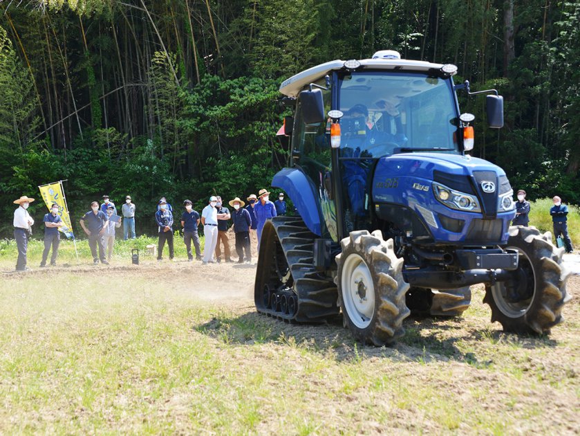 参加者の前で、自動操舵システムを搭載したトラクターを使って排水対策作業を実演してみせる農機具メーカーの担当者